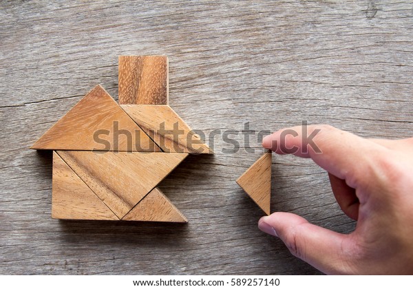 Wooden\
tangram puzzle wait to fulfill home shape for build dream home,\
happy life, house or mortgage investment\
concept