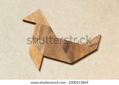 Wooden tangram in seal or sea lion shape on wood background