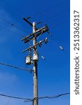 Wooden Telephone Pole With High Voltage Sign On Blue Sky And Lines At 90 Degrees 