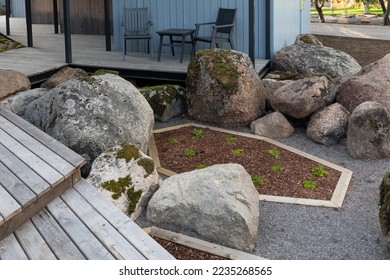 Wooden terrace of a Scandinavian-style country house with mossy boulders inscribed in the landscape
