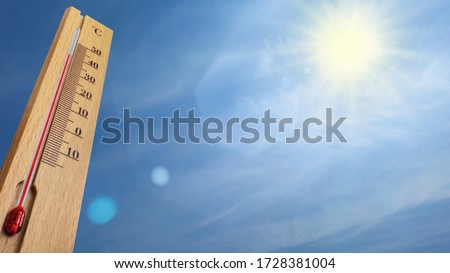 Wooden thermometer with red measuring liquid showing 40 degrees Celsius on a sunny day.
