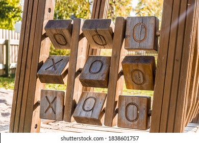 A wooden tic tac toe game for children in a playground. 