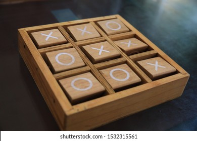 Wooden Tic-Tac-Toe game on the black desk 