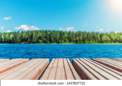 Wooden Timber Of A Rural Mooring On A Lake In The Middle Of The Forest. A Peaceful River Dock In The Woods.Sunny Footbridge. Minimal Background With Blue Sky,clean Lake And Mooring In The Country Side