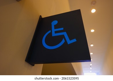 Wooden toilet sign with disability symbol. Icon board of a person with a wheelchair. Icon of a person in a wheelchair. Disabled people icon. Public toilets (WC) for people with disability
