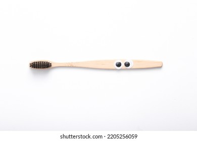 Wooden Tooth Brush With Eyes On White Background. Eco Concept