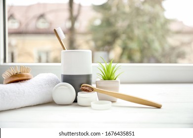 Wooden toothbrushes, toothpowder and dental floss in bathroom near window - Powered by Shutterstock
