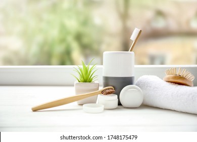 Wooden toothbrushes, toothpowder and dental floss in bathroom near window - Powered by Shutterstock