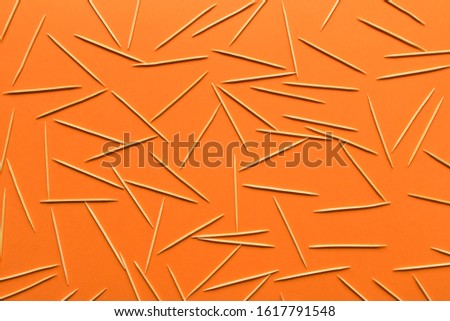 A lot of wooden toothpicks scattered on an orange background. Abstract background for the design