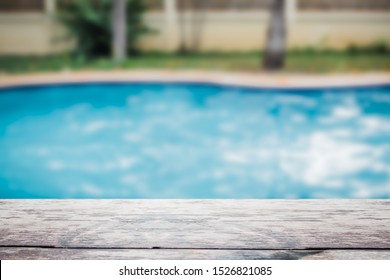Wooden top table foreground with the blur blue swimming pool in background. - Shutterstock ID 1526821085