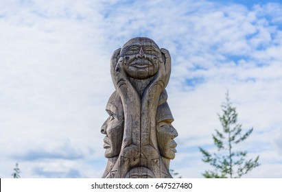 A wooden totem pole in British Columbia Canada at blue sky background