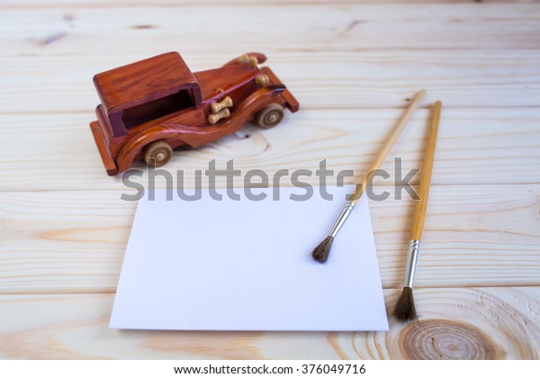 Wooden toy car and a brush to paint on the\
wooden background