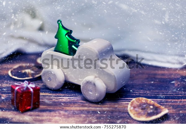 Wooden toy car delivering Christmas or New Year\
tree, blurred and snow