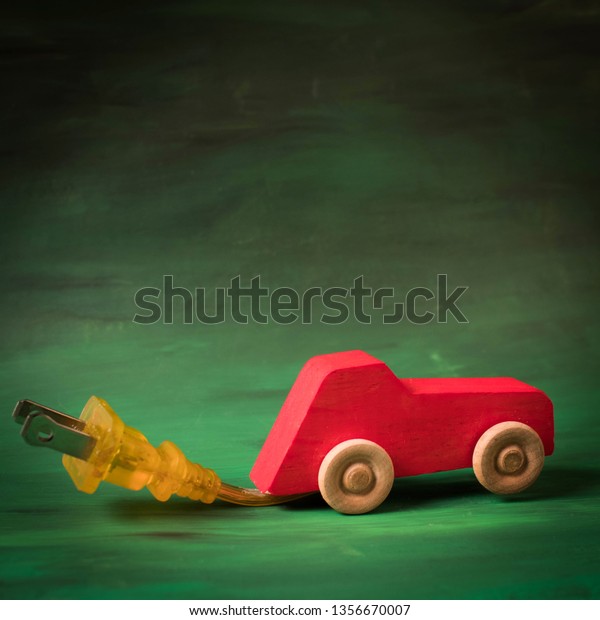 Wooden toy car with an electric plug for charging.\
Electric auto concept. Green, sustainable transportation\
technology. Save money and resources with environmentally friendly\
car. The future is\
green.