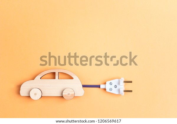 Wooden\
toy car with electrical cable plug as an electric car symbol. Save\
energy concept. Flat lay, copy space, top\
view.