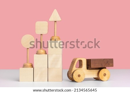 Wooden toy car truck and toy road signs stand on wooden cubes arranged in the form of a pyramid staircase. Mockup for delivery business, logistics.
