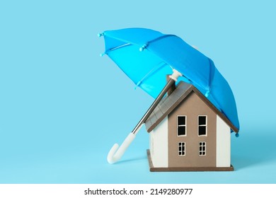 Wooden Toy House And Mini Umbrella On Color Background