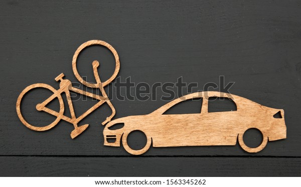 Wooden toy little car and bicycle\
on stone background. Concept  car accident with\
cyclist