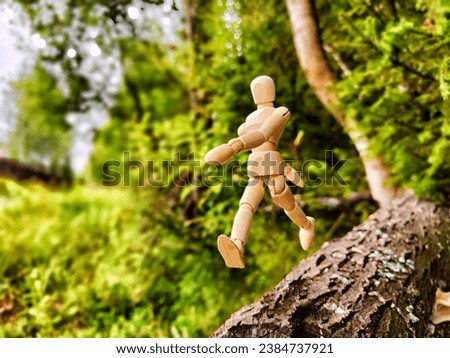 Wooden toy mannequin in forest among grass and trees in summer, autumn, spring. The concept of outdoor recreation and hiking. Healthy lifestyle. Earth Day. Save planet concept. Partial focus, blur