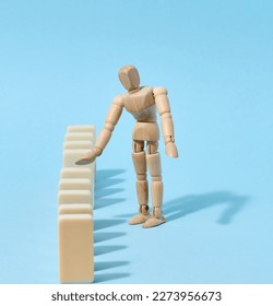 Wooden toy mannequin keeps dominoes from falling, risk prevention concept - Shutterstock ID 2273956673