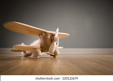 Wooden toy plane hand carved model on hardwood floor.