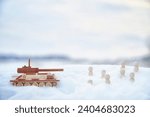 Wooden toy Russian tank T-34 and little men in the snow. Russia and Ukraine are at war in winter. Encirclement, retreat, attack, victory