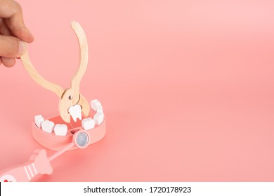 Wooden Toy Set Flat Laying On The Pink Background In The Concept Of Dental Caries, Remove Tooth, Gum Disease, Toothache  And Having Good Health.