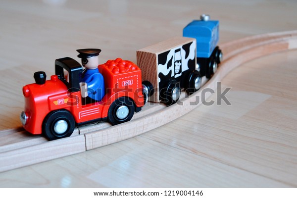 Wooden\
toy train. Train with driver runs on a wooden track system with\
grooves to guide the wheels of the rolling stock.\
