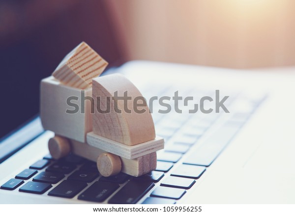 Wooden toy\
truck on laptop keyboard. Internet shopping, on-line purchase,\
e-commerce and packages delivery\
concept.