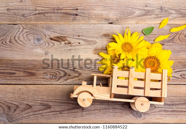 Wooden toy\
truck with yellow sunflowers in the back on rustic background.\
Space for text. Festive greeting\
concept.