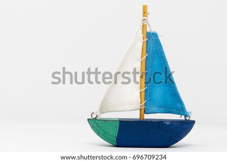 A wooden toy yacht. The toy boat shows signs of use, but the sails are in tact and still attached to the wooden mast. It is painted in 4 colours with a simple keel indicating this toy is ornamental.