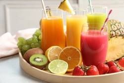 Wooden Tray With Glasses Of Different Juices And Fresh Fruits On Table