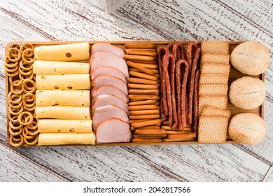 Wooden Tray With Meat And Cheese, Antipasto Snacks. Antipasto Cold Meat Dish With Breadsticks, Prosciutto, Ham, Ham Slices And Cheese On A Wooden Tray Top View, Flat Lay