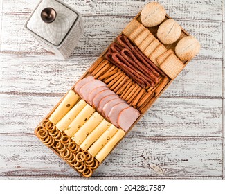 Wooden Tray With Meat And Cheese, Antipasto Snacks. Antipasto Cold Meat Dish With Breadsticks, Prosciutto, Ham, Ham Slices And Cheese On A Wooden Tray Top View, Flat Lay