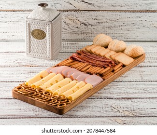 Wooden Tray With Meat And Cheese, Antipasto Snacks. Antipasto Cold Meat Dish With Breadsticks, Prosciutto, Ham, Ham Slices And Cheese On A Wooden Tray