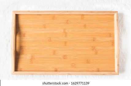 Wooden tray on light background. Empty tray in bed. Top view