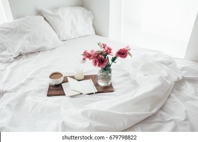 Wooden tray with paper sketchbook, candle and spring flowers on clean white bedding. Good morning concept. - Powered by Shutterstock