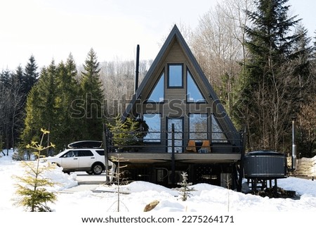 Wooden triangle country tiny cabin house with hot tub spa and suv car with roof rack in mountains. Soul weekends.