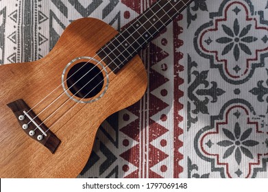 wooden ukulele close-up on a textured material with pattern. beautiful background in folk style