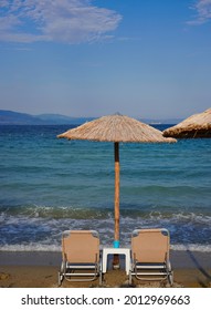 Wooden Umbrella With Two Lounge Chairs Near The Sea