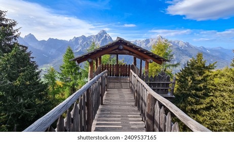 Wooden viewing platform connected by bridge with vistas to majestic mountain ranges of untamed Sexten Dolomites, South Tyrol, Italy. Lookout from mount Helm (Monte Elmo), Carnic Alps, Austria border