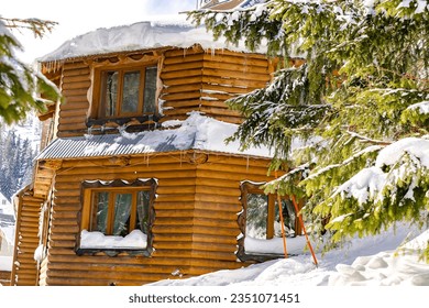 Wooden village rural house,mansion,hotel covered in snow,big icicles in winter forest mountains,Green spruce pine trees,nature. Calm countryside. Home residence in coniferous trees.Eco concept.