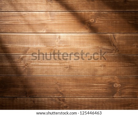 Wooden wall background in a morning light. With shadows from a window frame.