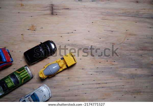 wooden wallpaper with 5 toy cars in the lower\
left corner.