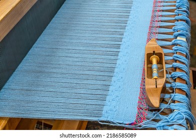 Wooden weaving loom used to weave thread or yarn into cloth, a rug or a tapestry. A loom holds  parallel threads under tension while enabling the weaving of another set of threads under tension.