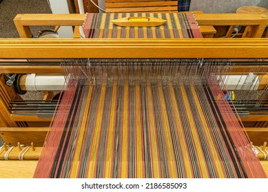 Wooden weaving loom used to weave thread or yarn into cloth, a rug or a tapestry. A loom holds  parallel threads under tension while enabling the weaving of another set of threads under tension.