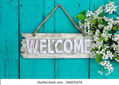 Wooden welcome sign with spring tree blossoms border hanging on antique teal blue wood background - Powered by Shutterstock