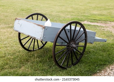 A Wooden Wheel Barrow With A Water Jug And Two Steel Wheels