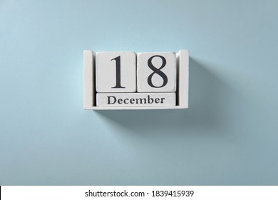 Wooden white calendar on blue background, date 18 December
