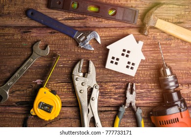 Wooden white house toy and construction tools on wooden background with copy space.Real estate concept, New house concept, Finance loan business concept, Repair maintenance concept